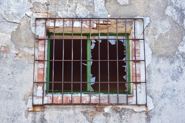 Ventana de una  vieja casa enrejada y con los cristales rotos