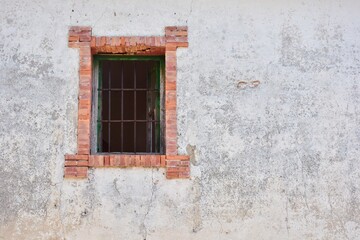 Fototapeta na wymiar Ventana con marco de ladrillo en la fachada de una vieja casa 