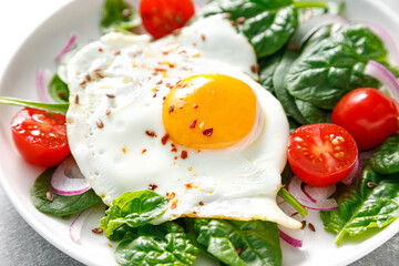 Fried egg with fresh spinach tomato salad for healthy breakfast