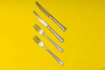 Cutlery lying on a yellow background, minimalism
