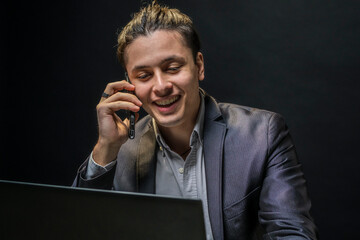 Young businessman receives good news on a business call in formal wear sitting in the office. Business, entrepreneurship, leadership concept