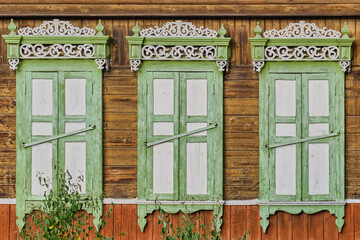 Old wooden painted white green windows, door. Carved architraves, closed shutters. Ulan-Ude, Russia.