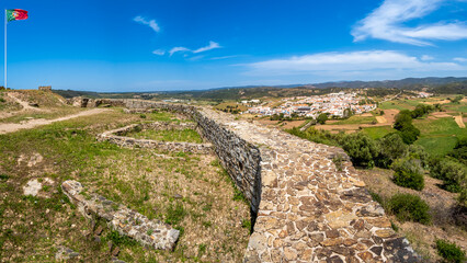Fototapeta na wymiar Panoramic view from the elevated ruins of the famous castle Castelo de Aljezur over rural farmland with the river Ribeira da Cerca to Aljezur village in the distance in the Algarve area of Portugal.