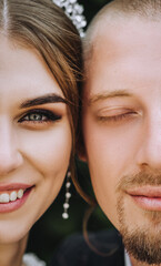 Close-up half faces of a stylish, young groom and a beautiful bride with a diadem on their heads. Wedding photography of smiling newlyweds, portrait.