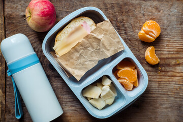 schoolboy lunch box with thermos on wooden background.apple,tangerine,sandwich in lunchbox and...