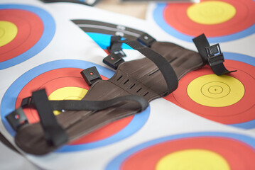 Leather gauntlet for hunting or archery lies on a pack of shooting range targets
