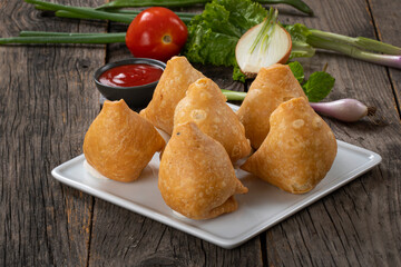 Fried indian dish singaraa.Indian Delicious Deep Fried Breakfast Samosa Also Know as Samoosa isolated on Wooden texture Background