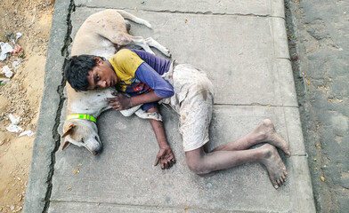 Homeless kid sleeping with his dog on the street. Concept of poverty, social differences, cruelty....