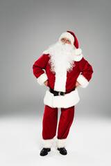 Pensive santa claus in costume looking away on grey background.