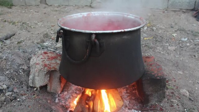 Tomatoes boiled in a cauldron on a hot fire turn into tomato paste.