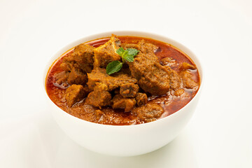 Beef masala or roast,kerala style homemade recipe garnished with coconut pieces and curry leaves which is arranged in white bowl with white background