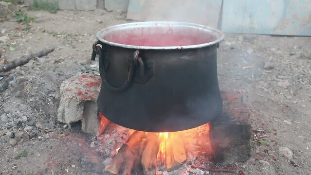 Tomatoes boiled in a cauldron on a hot fire turn into tomato paste.