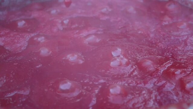 Tomatoes boiled in a cauldron on a hot fire turn into tomato paste.