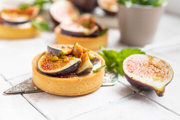 Tasty tartlets with cream cheese and figs on grey tilled background. Cooking concept. Healthy dessert.