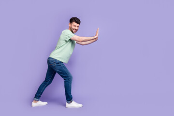 Fototapeta na wymiar Full body photo of attractive young guy pushing hard copyspace difficult wear trendy gray clothes isolated on violet color background