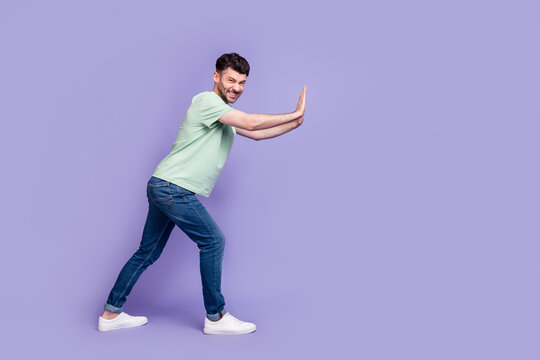 Full body photo of attractive young guy pushing hard copyspace difficult wear trendy gray clothes isolated on violet color background