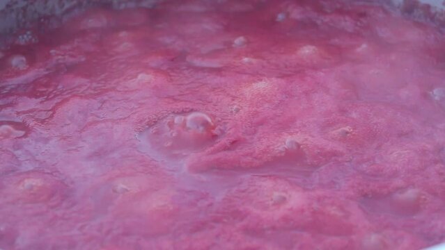Tomatoes boiled in a cauldron on a hot fire turn into tomato paste.