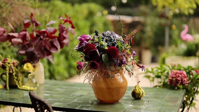 Beautiful autumn bouquet in vase on table in garden, pan camera movement