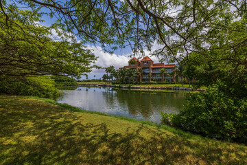 Beautiful landscape view of pond in front of hotel buildings surrounded with green trees. Aruba