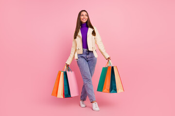 Full length photo of sweet stylish millennial lady go look advert hold bags wear casual cloth boots isolated on pastel pink color background