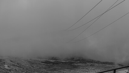 Fototapeta premium Cable car cables coming out of the clouds in Austrian Alps glacier