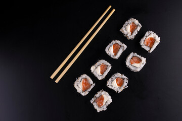 japanese food in with four side by side salmon sushi rolls and cream cheese and chopsticks seen top view landscape
