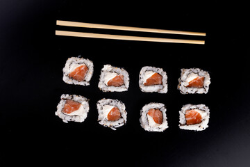 japanese food in with four side by side salmon sushi rolls and cream cheese and chopsticks viewed top view
