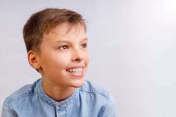Boy is wearing orthodontic silicone trainer or night-guard case. Invisible braces helps of orthodontics problem. Close-up portrait. Mobile appliance for dental teeth correction.