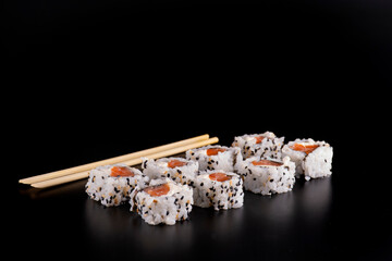japanese food with four side-by-side salmon sushi rolls and cream cheese and chopsticks seen almost from the front