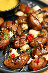 Fototapeta na wymiar Appetizing juicy grilled mushrooms on a dark plate with spices. Macro.