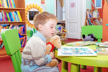 An attentive kid studies the contents of a children's book while sitting in the reading room of the library. The child is drawn to knowledge
