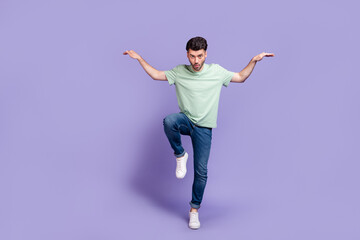 Full length photo of crazy focused man dressed fashionable clothes denim stand one leg foot empty space isolated on purple color background © deagreez
