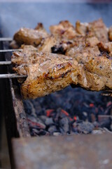a man roasts meat on a fire. Close-up of hands and shish kebab. Cooking pork neck on the grill. Roasted carrots. Fatty food, festive food of the CIS countries. May 1, labor day. Not vegan food	