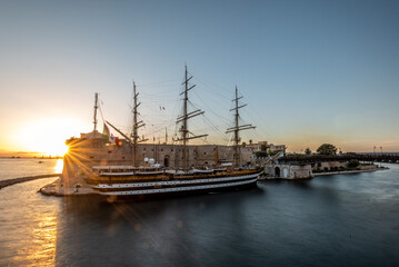 Fototapeta premium The Italian Navy Historical Ship Called Amerigo Vespucci Moored in front of the Aragonian Castle in the Canalboat of Taranto at Sunset, in the South of Italy