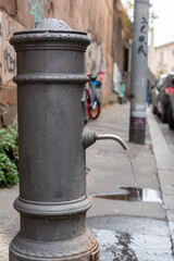 Fototapeta na wymiar Close-up of a characteristic fountain of Rome called Nasone from which water comes out into the street