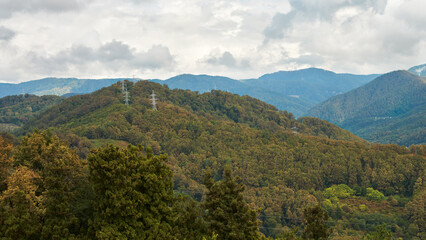 Mountain relief with metal poles of the power line passing through the top of the mountain.