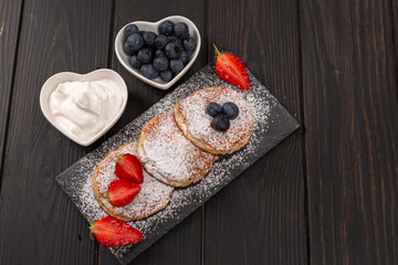 Cottage cheese cakes, sprinkled with powdered sugar and decorated with fresh berries