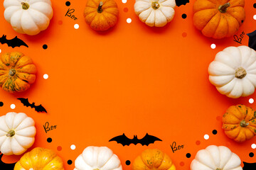 Halloween flat lay composition of black paper bats and pumpkins on orange background. Halloween concept