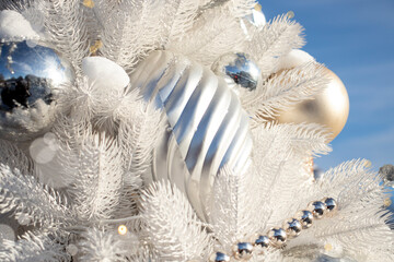 Christmas tree decorated with white balls and toys in the snow