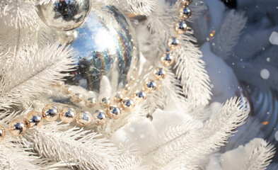 Christmas tree decorated with white balls and toys in the snow