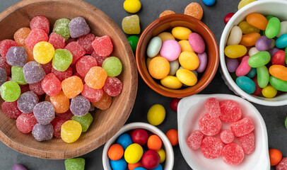 Fototapeta na wymiar Assorted colorful candies in bowls over stone background
