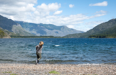 Rear view of a boy throwing stones in lake