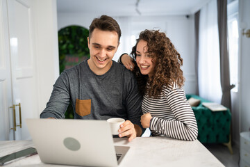 happy couple using laptop computer with cup of coffee morning routine