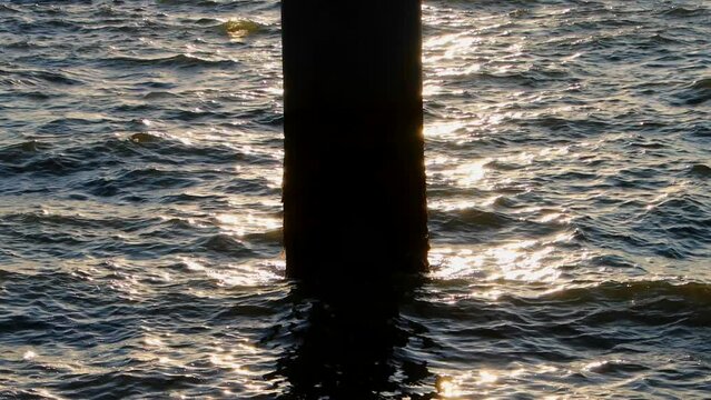 Sun setting behind a pole reflecting in the water