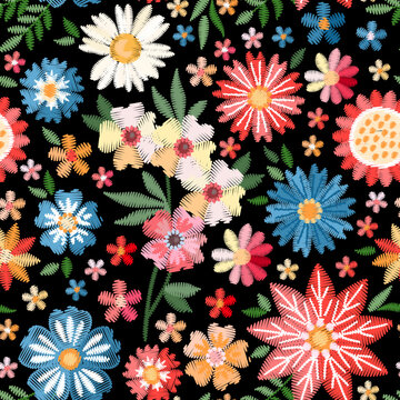 Colorful seamless pattern with embroidered flowers. Vivid embroidery on black background. Fabric print with bright floral motifs