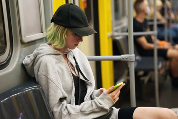 Teenage girl with smartphone rides in a subway train.