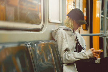 Teenage girl with smartphone rides in a subway train.