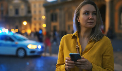 Woman with smartphone lost in the evening city.