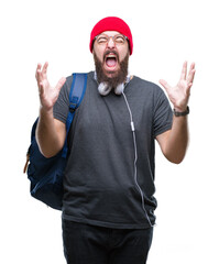 Naklejka premium Young hipster man wearing red wool cap and backpack over isolated background crazy and mad shouting and yelling with aggressive expression and arms raised. Frustration concept.