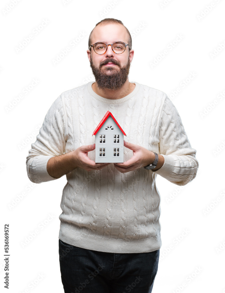 Sticker Young caucasian real state agent man holding house isolated background with a confident expression on smart face thinking serious